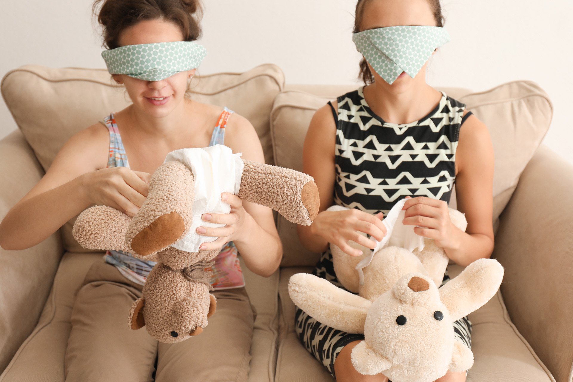 mujeres con los ojos vendados tratando de vestir un peluche