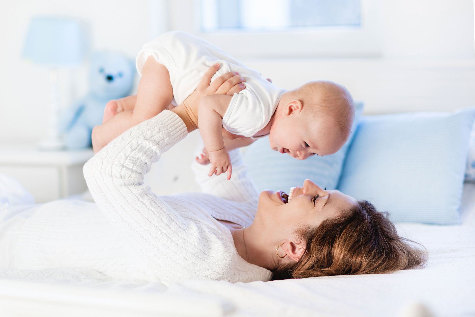 Mamá cargando a su bebé en la cama