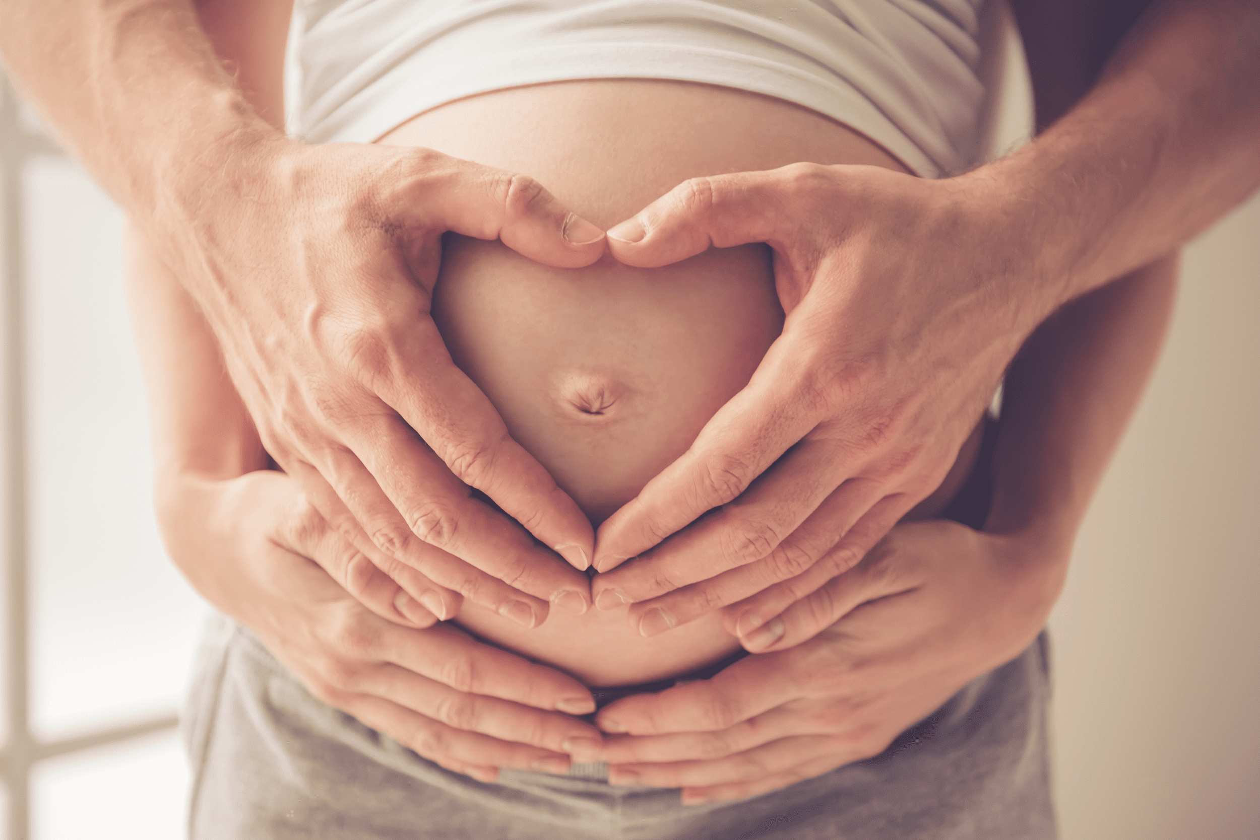 Papás formando un corazón en barriga embarazada