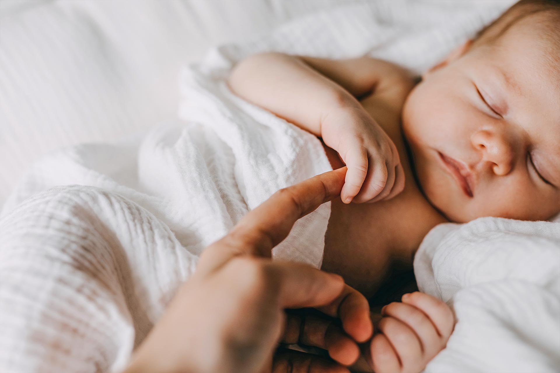 Bebé sujetando el dedo de su mamá