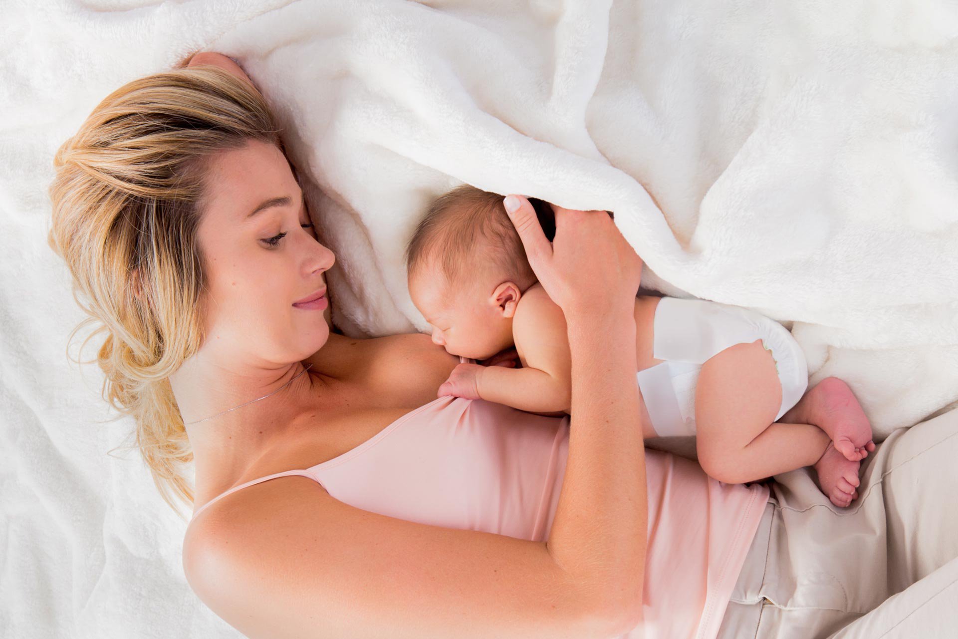 Mamá acostada con su bebé recién nacido