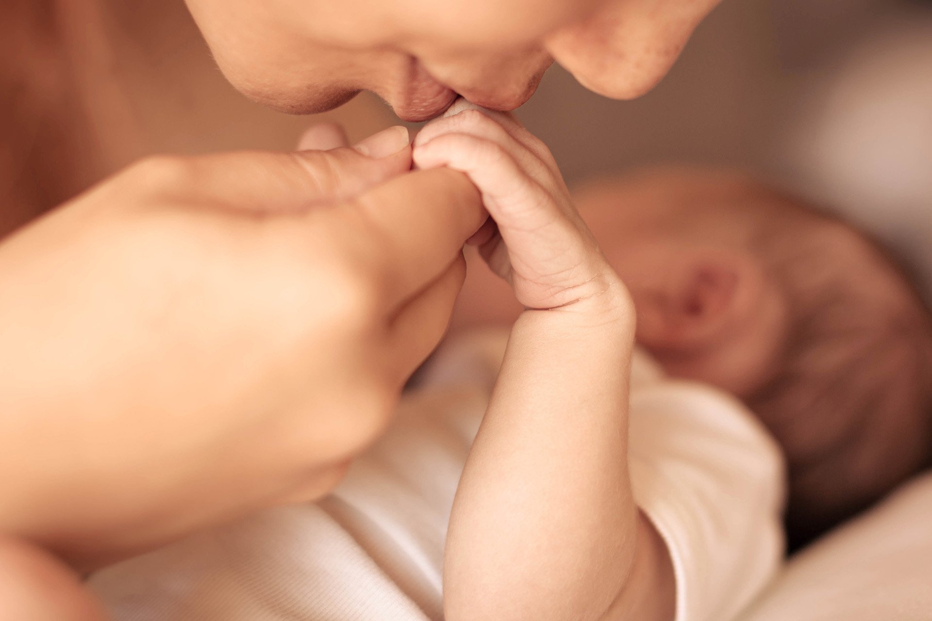 Mamá besando la mano de su bebé.