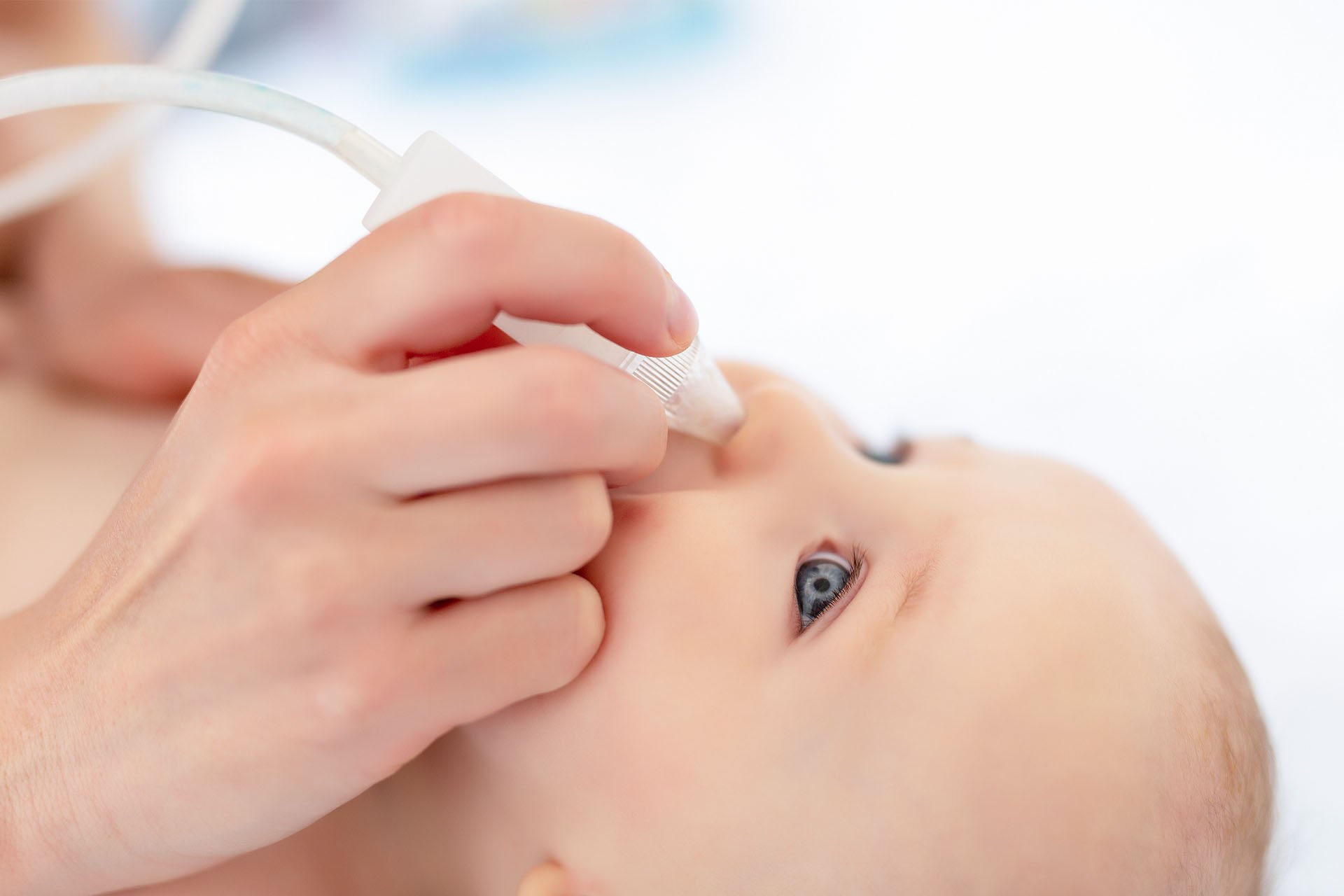 Mamá limpiando la nariz de su bebé.