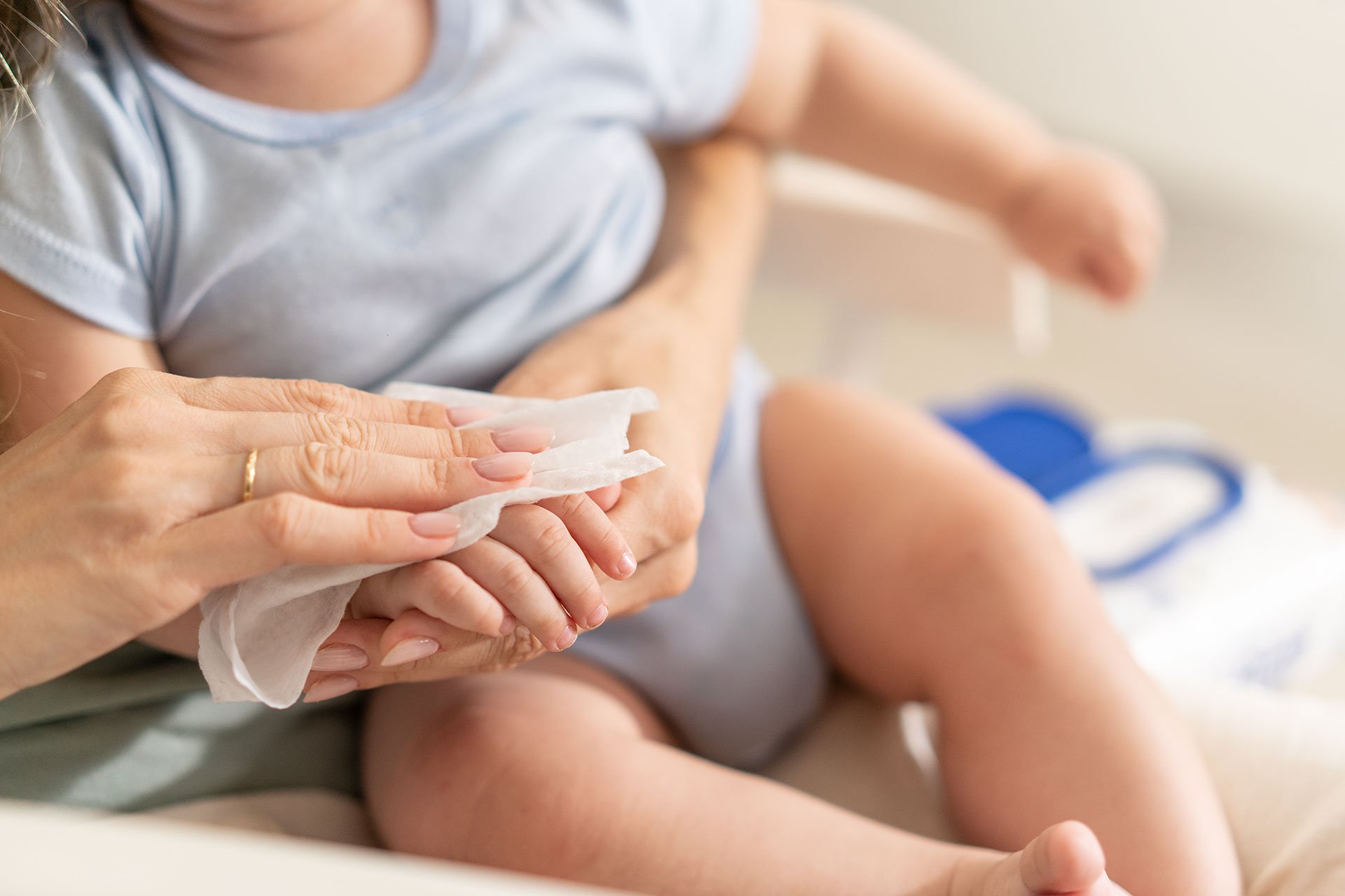 Mamá limpiando las manos de su bebé con toallitas húmedas